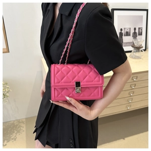 Detail view of pink quilted chain bag with silver rotating lock on a black suit
