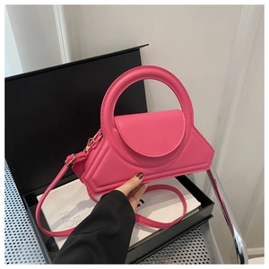 Dettaglio della borsa geometrica rosa con manico circolare su un libro decorativo