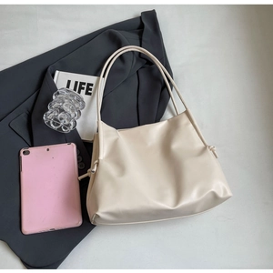 Detail view of large cream-white PU leather tote bag with knot drawstrings and long strap
