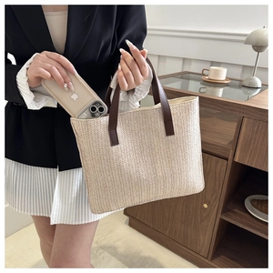 Detail of woven tote bag showing its capacity to hold a large smartphone and leather handle