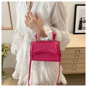 Detail of rose pink handbag with knotted handle and elegant wave stitching worn by a model