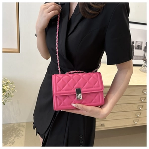 Detail of rose pink quilted crossbody bag with metal chain strap on female model