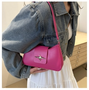 Close-up of bright pink leather underarm bag with a silver star buckle on denim jacket