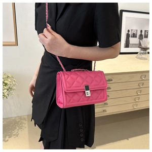 Détail du sac bandoulière fuchsia matelassé avec fermoir métallique sur robe noire