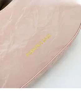 Close-up of pink crescent bag with marble texture leather and gold fashion lettering