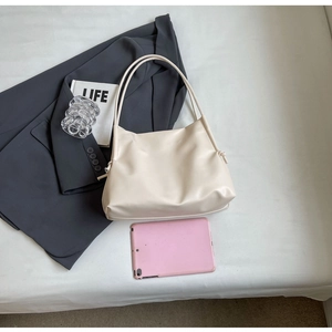 Flat lay of cream faux leather shoulder bag with drawstring detail and large capacity