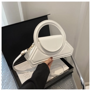 Dettaglio di una borsa geometrica bianca con manico rotondo in una confezione regalo