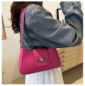 Detail of rose red shoulder bag with silver star hardware on a denim outfit