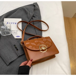 Detail of a brown vintage crossbody bag featuring geometric texture and golden ring buckle