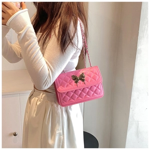 Détail du sac à bandoulière rose matelassé avec fermoir papillon et bandoulière chaîne