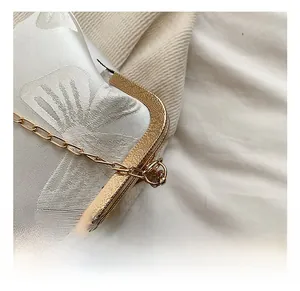 Close-up of golden floral metal frame and white silk jacquard fabric on dinner bag