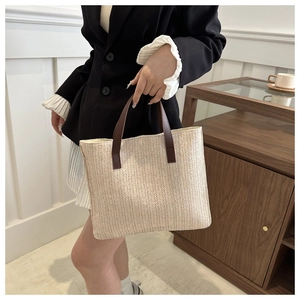 Detail of hand-woven straw tote bag with premium dark brown leather handle accessory