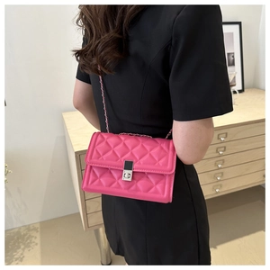 Close-up of pink quilted leather crossbody bag with silver chain and metal lock