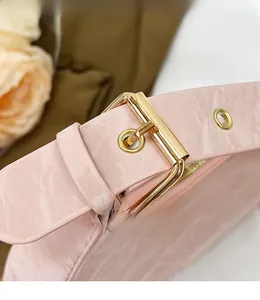 Detailed close-up of pink patent leather shoulder bag with adjustable gold buckle