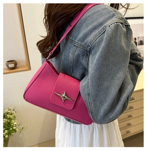 Detail of rose pink baguette bag with silver star hardware on a model in a home studio