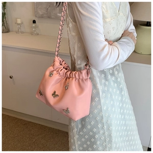 Detailansicht der rosa Kordelzug-Beuteltasche mit silbernen Schmetterlingen und Kette