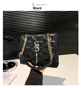 Close-up of black quilted shoulder bag with golden S logo and elegant fringe detail