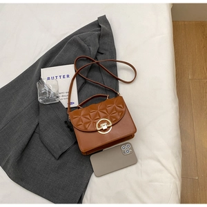 Detailed close-up of brown quilted faux leather crossbody bag with golden ring buckle