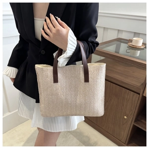 Detail view of beige woven tote bag with brown handles and herringbone texture