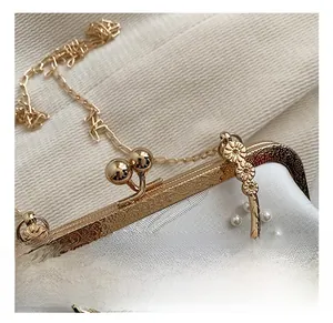 Detail of vintage golden clasp with ornate engraving and pearls on white satin bag