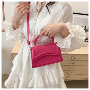 Detail of rose pink handbag featuring unique knotted handle and wave pattern flap design
