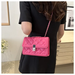 Detail of rose pink quilted crossbody bag with silver chain strap on model shoulder