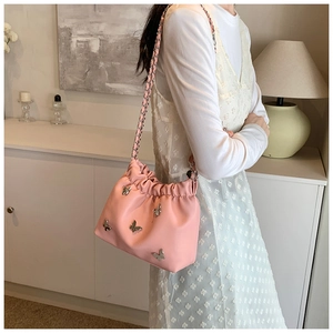 Detail der rosa gefalteten Beuteltasche mit Schmetterlingsakzenten und Silberkette