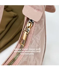 Detail shot of smooth gold-tone zipper slider on a pink leather crescent handbag