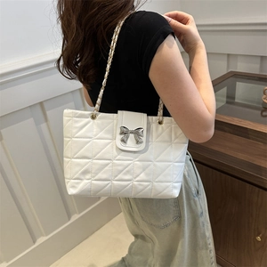 Minimalist white quilted shoulder bag with silver bow accent and chain strap shown on model