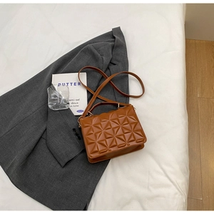 Detail of caramel quilted crossbody bag featuring geometric texture on a grey blazer