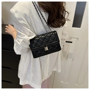Detail of black quilted leather shoulder bag featuring a metallic chain and classic turn-lock