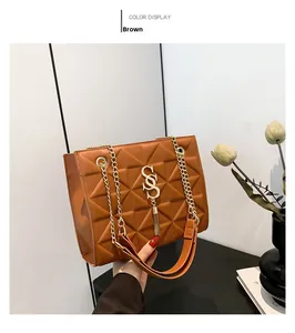 Detail of brown geometric quilted shoulder bag featuring gold S-shaped clasp and chain strap