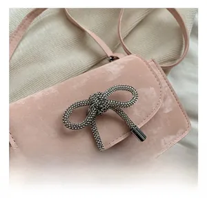 Close-up of pink leather handbag featuring a large rhinestone bow buckle and fine hardware