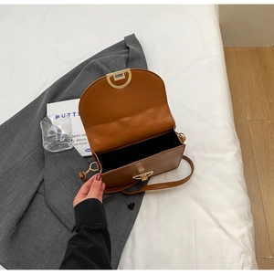 Detail of caramel leather bag interior with golden horseshoe clasp and black lining