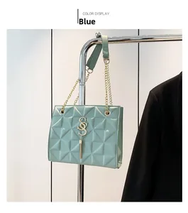 Detail of mint green quilted shoulder bag with gold S-letter logo and tassel pendant