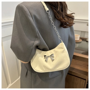 Detail of a chic cream-white underarm bag with a silver metallic bow and chain strap
