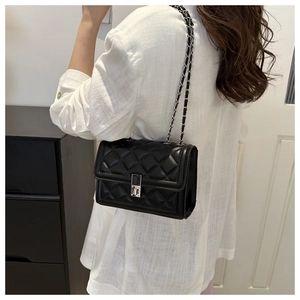 Detail of black quilted leather shoulder bag with silver chain strap and metal lock buckle
