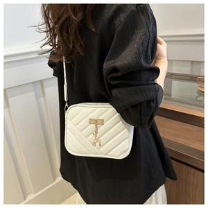 Detail of white V-quilted faux leather crossbody bag with a gold deer charm and thin strap