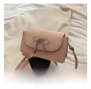 Detailed close-up of pink crossbody bag featuring a silver rhinestone bow metal buckle