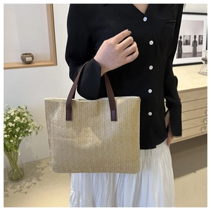 Detail of handwoven beige tote bag featuring premium brown leather handles and textured patterns