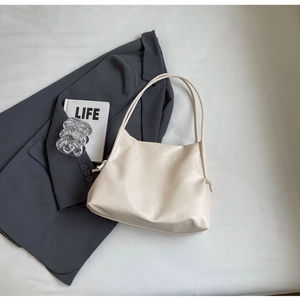 Close-up of cream textured leather tote bag with knotted strap and drawstring side detail