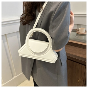 Vista dettagliata di una borsa geometrica bianca con manico rotondo indossata a spalla