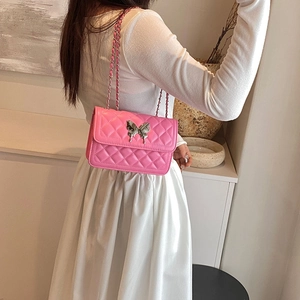 Sac bandoulière rose matelassé avec boucle papillon argentée et chaîne sur le mannequin