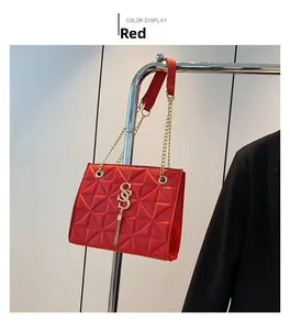 Detail of red quilted leather crossbody bag with gold chain strap and metallic tassel charm