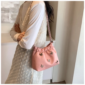 Seitenansicht der rosa Beuteltasche mit silbernen Schleifen am Modell im weißen Kleid