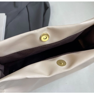 Detail of magnetic snap closure and brown fabric lining on cream tote bag