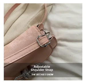Detail of adjustable shoulder strap and sparkling crystal bow decoration on pink bag