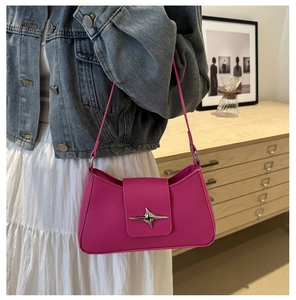 Detail of fuchsia underarm bag featuring a silver star ornament and sleek leather texture