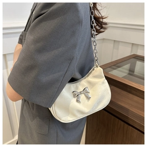 Detail of white silk shoulder bag with silver bow ornament and chunky metal chain