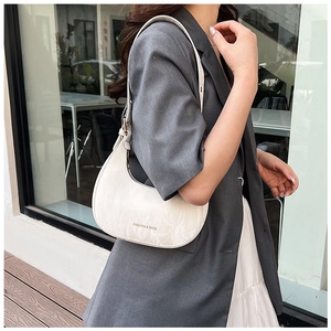 Close-up of cream crescent bag with delicate embossed texture and brand text detail